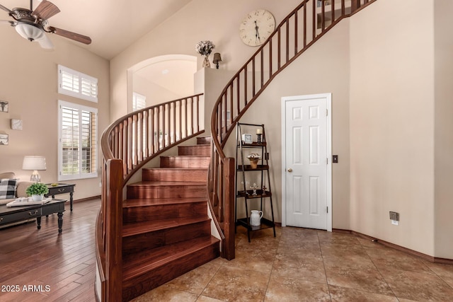 stairway with baseboards, a high ceiling, and ceiling fan