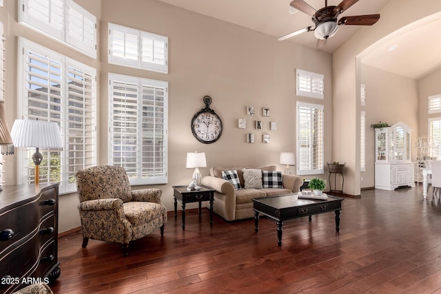 living area featuring ceiling fan, a high ceiling, and dark wood finished floors