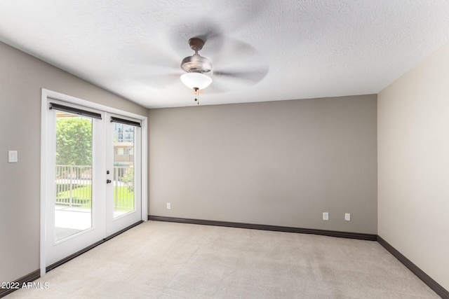 carpeted spare room featuring ceiling fan, a textured ceiling, and french doors