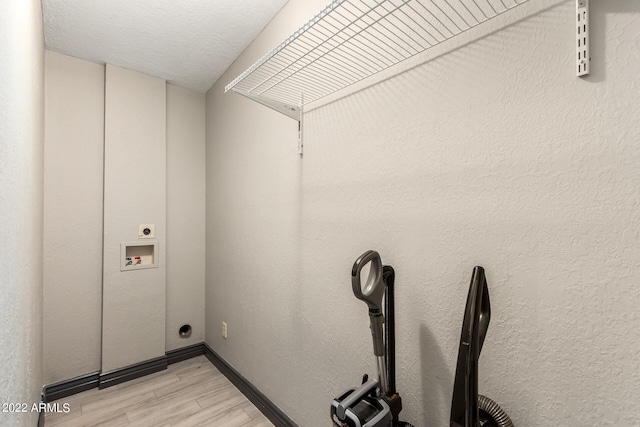 laundry area featuring washer hookup, a textured ceiling, light hardwood / wood-style floors, and hookup for an electric dryer