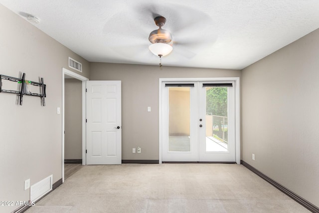 carpeted empty room featuring ceiling fan, a textured ceiling, and french doors