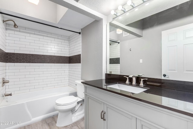 full bathroom featuring toilet, tiled shower / bath, hardwood / wood-style flooring, and vanity