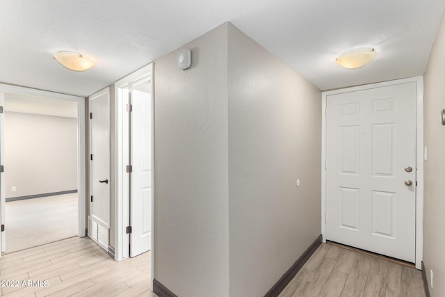 hallway with a textured ceiling and light hardwood / wood-style flooring