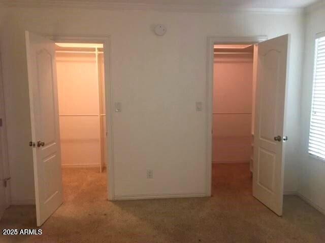 unfurnished bedroom featuring light carpet, multiple windows, and ornamental molding