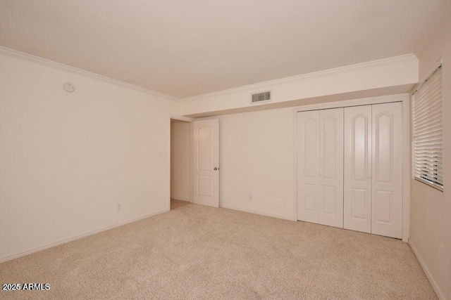 unfurnished bedroom with ornamental molding, light carpet, and a closet