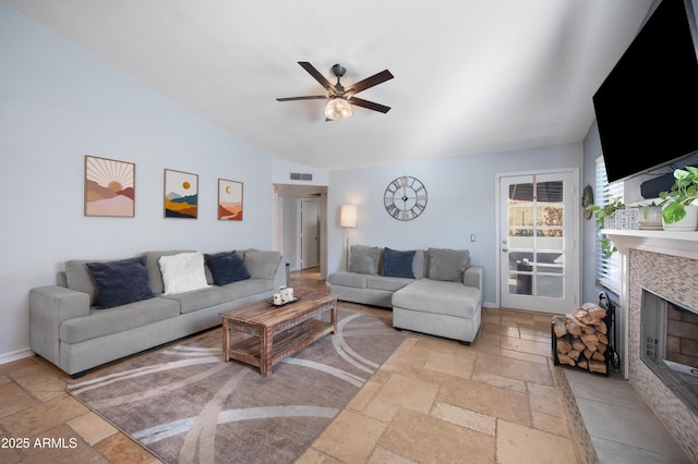 living room featuring a tile fireplace, ceiling fan, and lofted ceiling