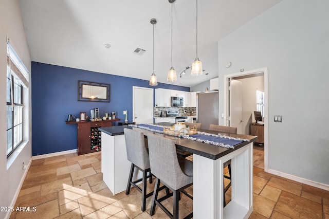 kitchen with tasteful backsplash, pendant lighting, a breakfast bar area, white cabinets, and appliances with stainless steel finishes