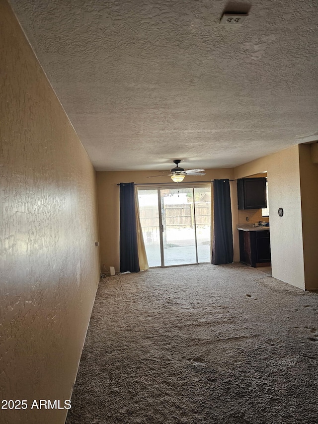 empty room with carpet floors, a textured ceiling, and ceiling fan