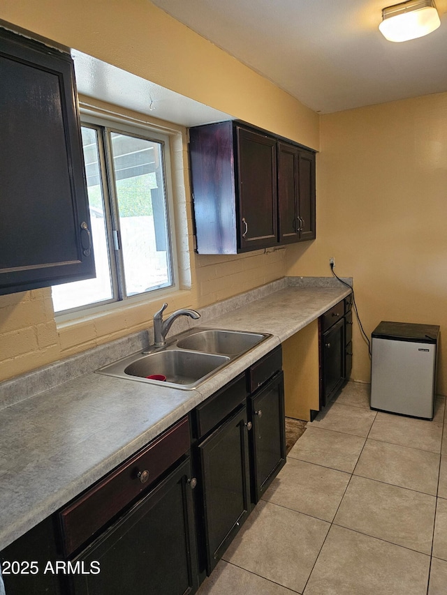 kitchen featuring light tile patterned floors, sink, and stainless steel refrigerator