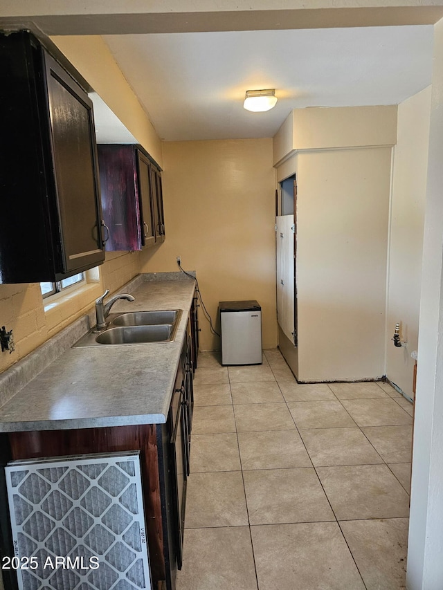 kitchen featuring light tile patterned floors, sink, and dark brown cabinetry