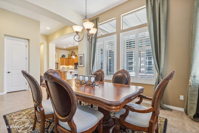 dining area featuring arched walkways, light tile patterned floors, recessed lighting, a notable chandelier, and baseboards