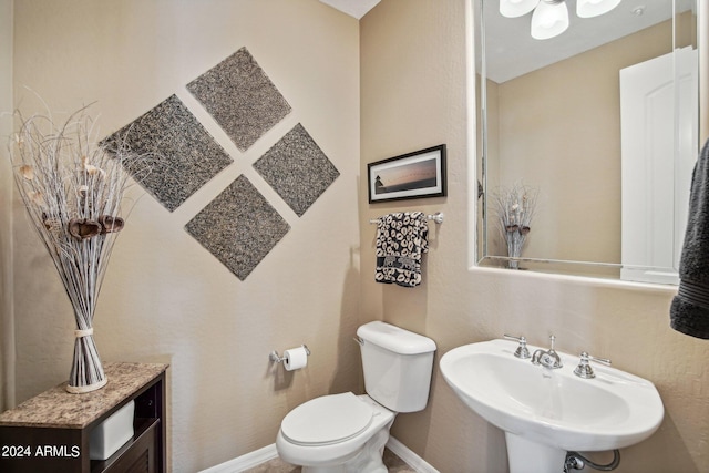 bathroom with baseboards, a sink, and toilet