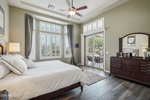 bedroom featuring a tray ceiling, access to exterior, ceiling fan, and dark wood-type flooring