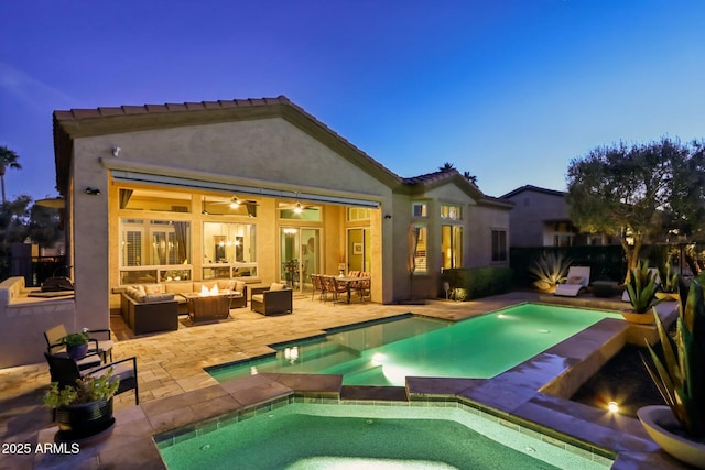 rear view of property featuring an outdoor living space with a fire pit, stucco siding, a pool with connected hot tub, a patio area, and ceiling fan