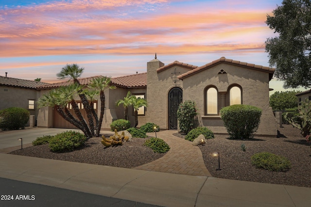 mediterranean / spanish-style house featuring driveway, a chimney, a tile roof, and stucco siding