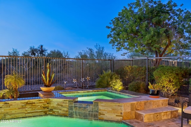 view of pool with a fenced in pool, fence, and an in ground hot tub