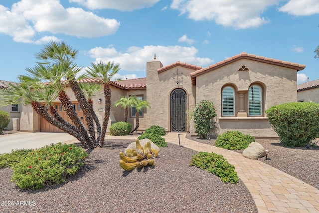 mediterranean / spanish-style house with a tiled roof, a chimney, concrete driveway, and stucco siding