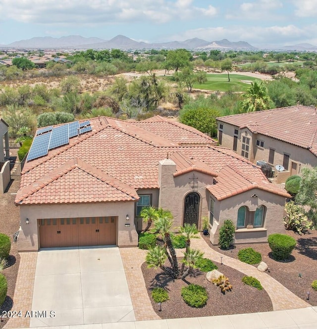 mediterranean / spanish-style house with a mountain view, a garage, and solar panels