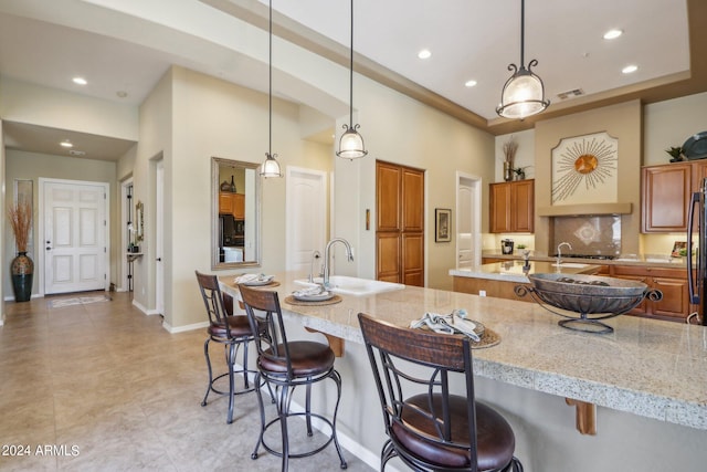 kitchen with pendant lighting, a sink, a large island with sink, and a breakfast bar area