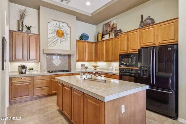 kitchen featuring light stone counters, a center island, visible vents, brown cabinets, and black appliances