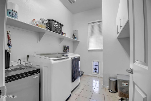 laundry area with washing machine and dryer, cabinets, and light tile patterned floors