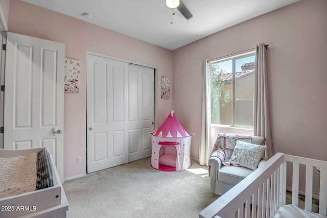 carpeted bedroom with ceiling fan, a nursery area, and a closet