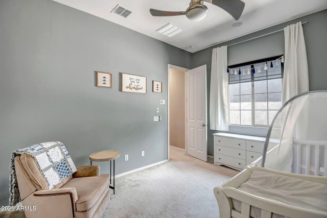 bedroom with light carpet, ceiling fan, and a crib