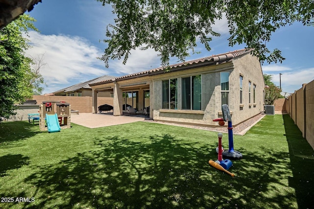 rear view of house with a playground, a patio area, central AC unit, and a lawn