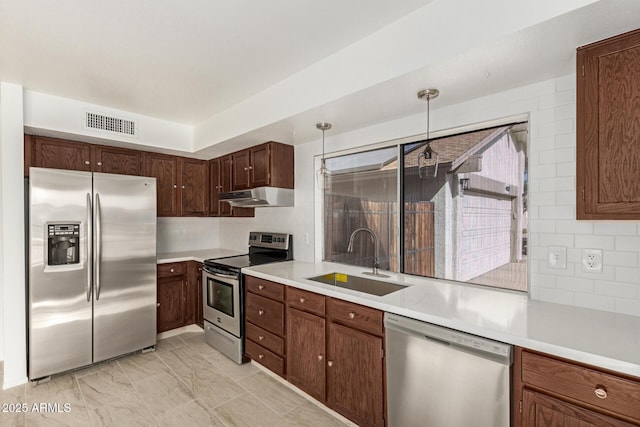 kitchen with pendant lighting, stainless steel appliances, sink, and backsplash