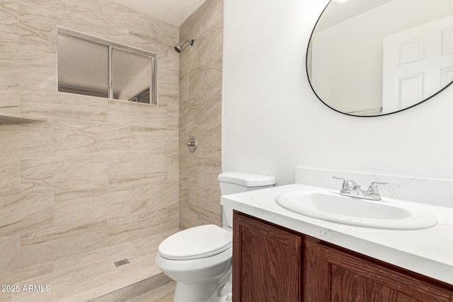 bathroom featuring tiled shower, vanity, and toilet