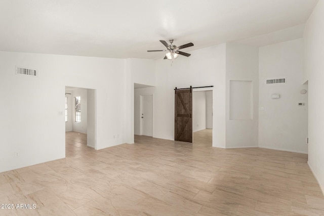 unfurnished room with a barn door, lofted ceiling, and ceiling fan