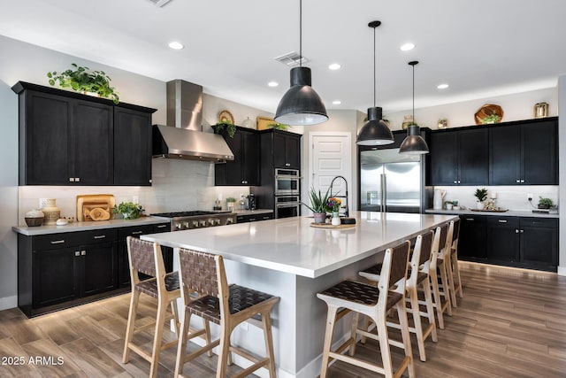 2037 E Fallen Leaf Ln, Phoenix, AZ 85024 - kitchen with wall chimney range hood, dark cabinets, stainless steel appliances, a kitchen bar, and tasteful backsplash