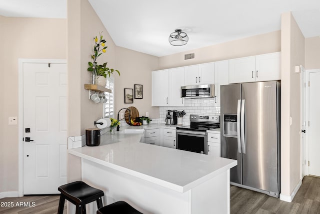 kitchen featuring white cabinetry, a breakfast bar, stainless steel appliances, and kitchen peninsula