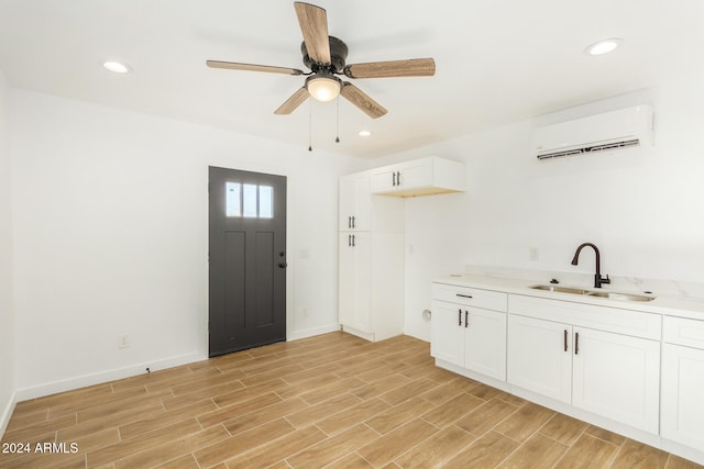 interior space featuring an AC wall unit, ceiling fan, sink, and light hardwood / wood-style floors