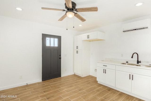 interior space featuring ceiling fan, a wall mounted AC, sink, and light hardwood / wood-style flooring