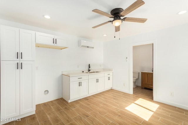 interior space with light hardwood / wood-style floors, an AC wall unit, sink, and ceiling fan