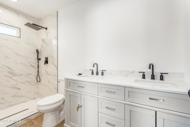 bathroom with tile patterned flooring, vanity, toilet, and a tile shower