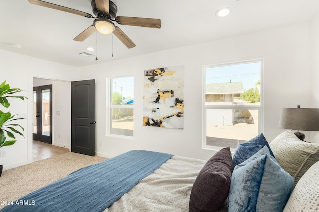 bedroom with ceiling fan, light colored carpet, and multiple windows