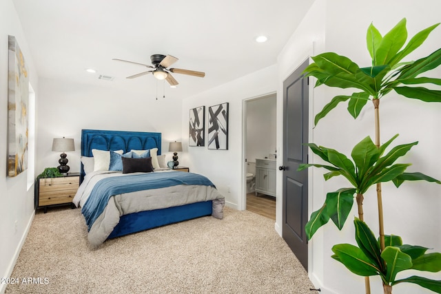 bedroom featuring connected bathroom, light carpet, and ceiling fan