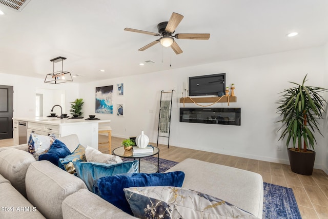 living room featuring ceiling fan, sink, and light wood-type flooring