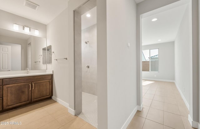 full bath featuring visible vents, vanity, a walk in shower, baseboards, and tile patterned floors