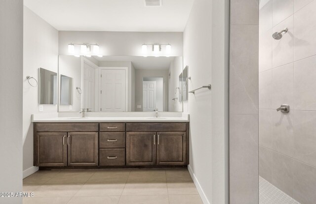 full bath featuring double vanity, visible vents, baseboards, and a sink