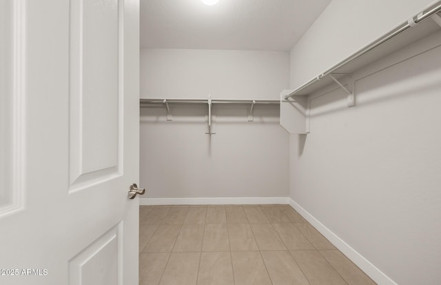 walk in closet with light tile patterned floors