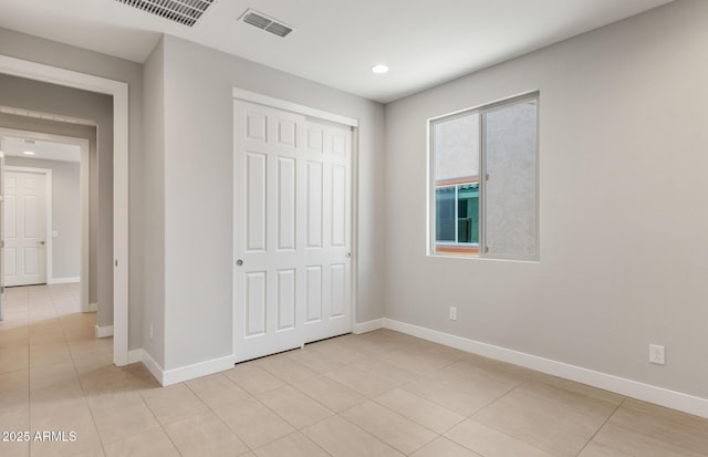 unfurnished bedroom featuring baseboards, visible vents, a closet, and light tile patterned flooring