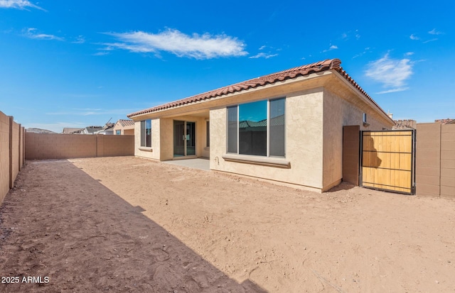 rear view of house with a patio, a tile roof, a fenced backyard, and stucco siding