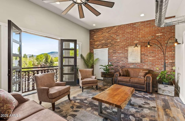 living area with brick wall, wood finished floors, and a healthy amount of sunlight