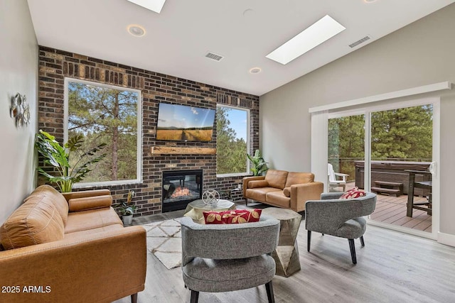 301 S O Leary St, Flagstaff, AZ 86001 - living area with vaulted ceiling with skylight, light wood-type flooring, a brick fireplace, and a wealth of natural light