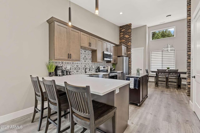 301 S O Leary St, Flagstaff, AZ 86001 - kitchen with tasteful backsplash, light wood-style flooring, appliances with stainless steel finishes, a kitchen island, and a kitchen bar