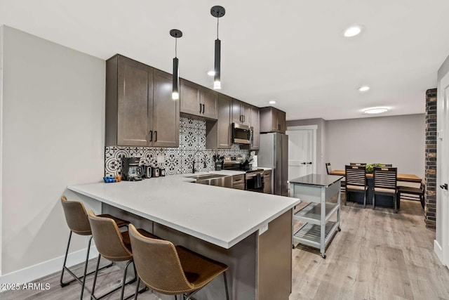 301 S O Leary St, Flagstaff, AZ 86001 - kitchen featuring dark brown cabinetry, a kitchen breakfast bar, light wood-style floors, appliances with stainless steel finishes, and decorative backsplash
