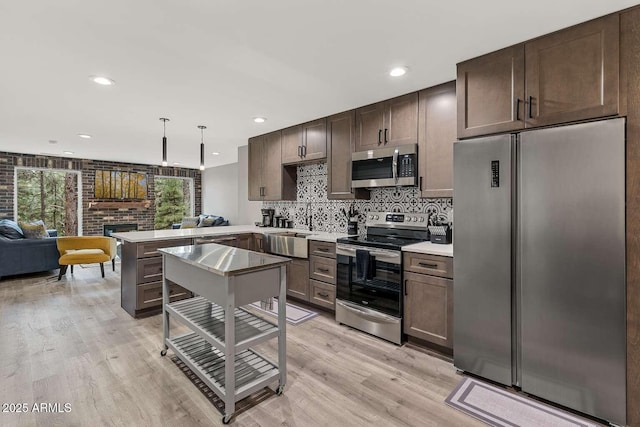 301 S O Leary St, Flagstaff, AZ 86001 - kitchen featuring appliances with stainless steel finishes, a peninsula, dark brown cabinets, a brick fireplace, and a sink
